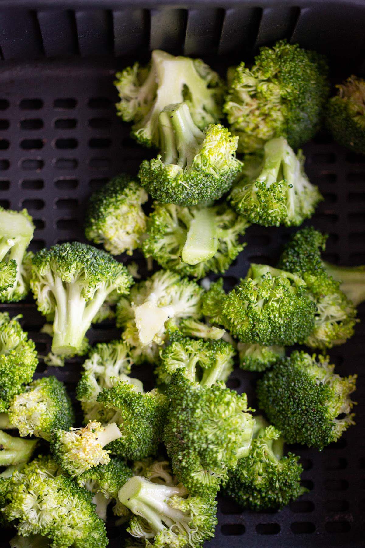 Uncooked broccoli in air fryer basket