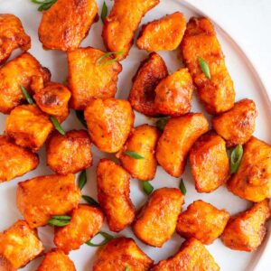 Air fryer buffalo chicken bites on a plate with green onions