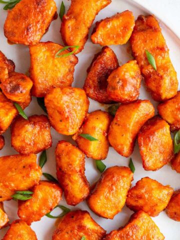 Air fryer buffalo chicken bites on a plate with green onions