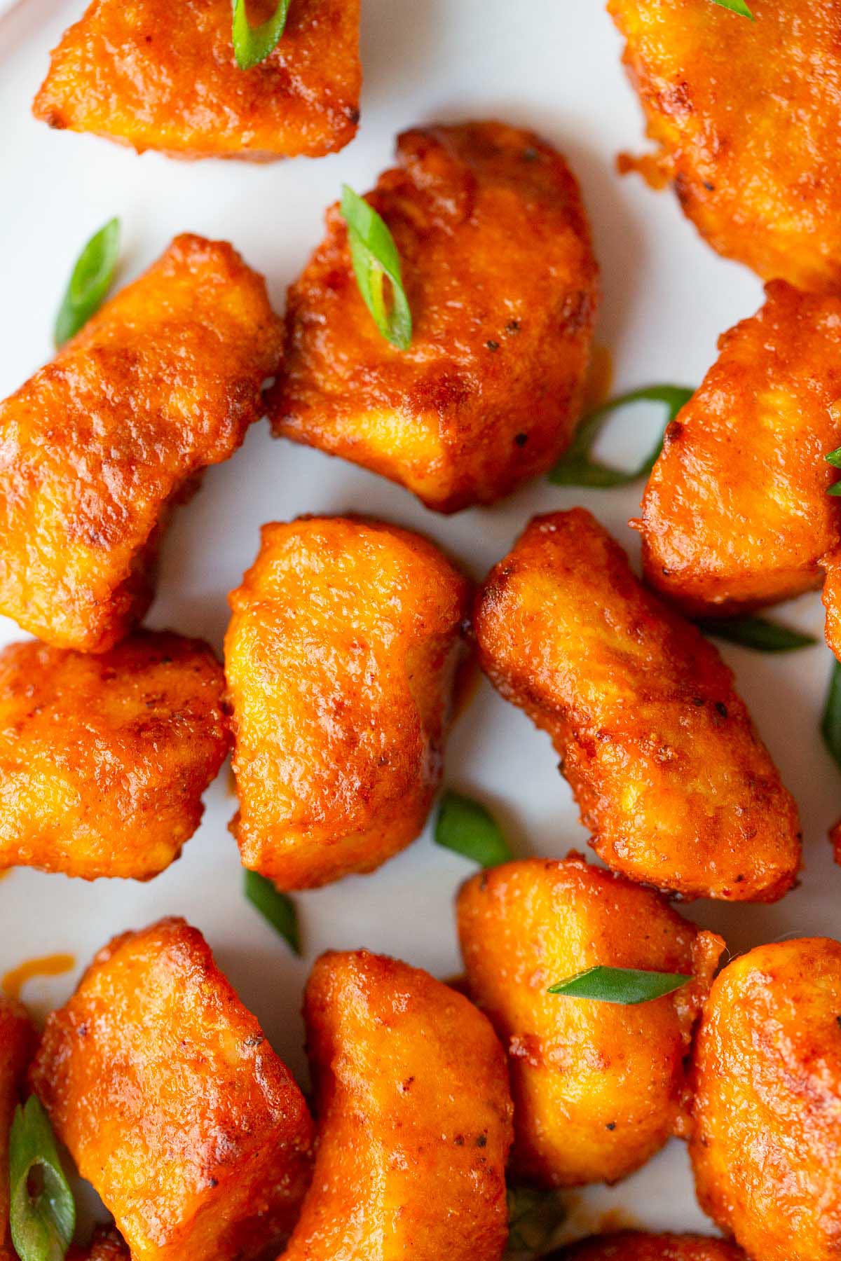 Air fryer buffalo chicken bites on a plate with green onions