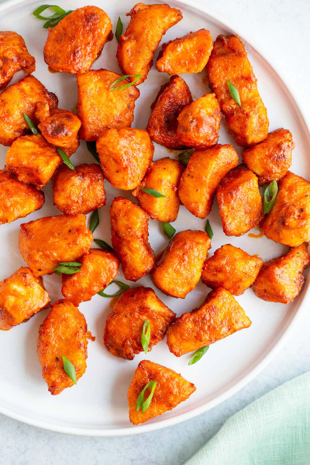 Air fryer buffalo chicken bites on a plate with green onions