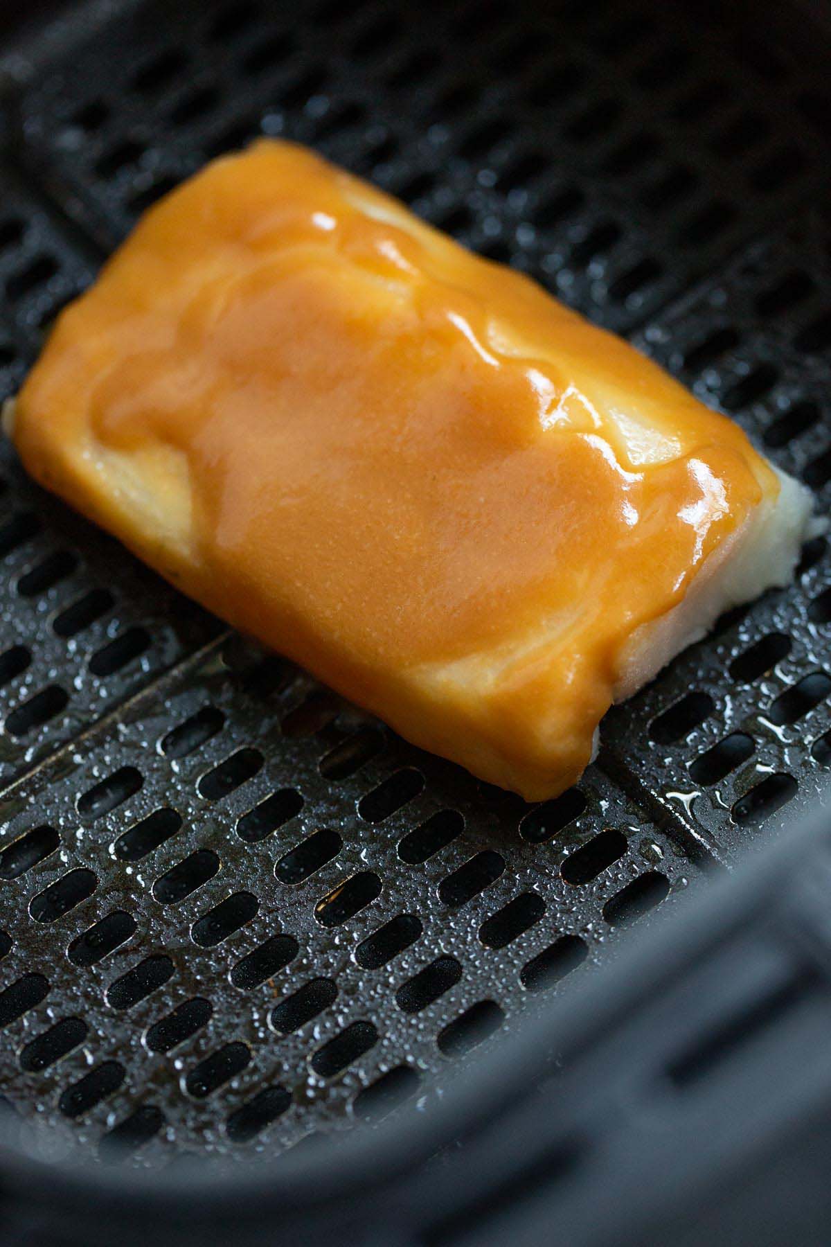 Uncooked cod with miso glaze in air fryer basket