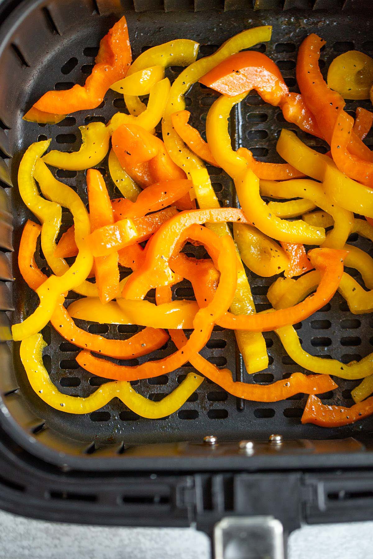 Uncooked bell peppers in air fryer basket