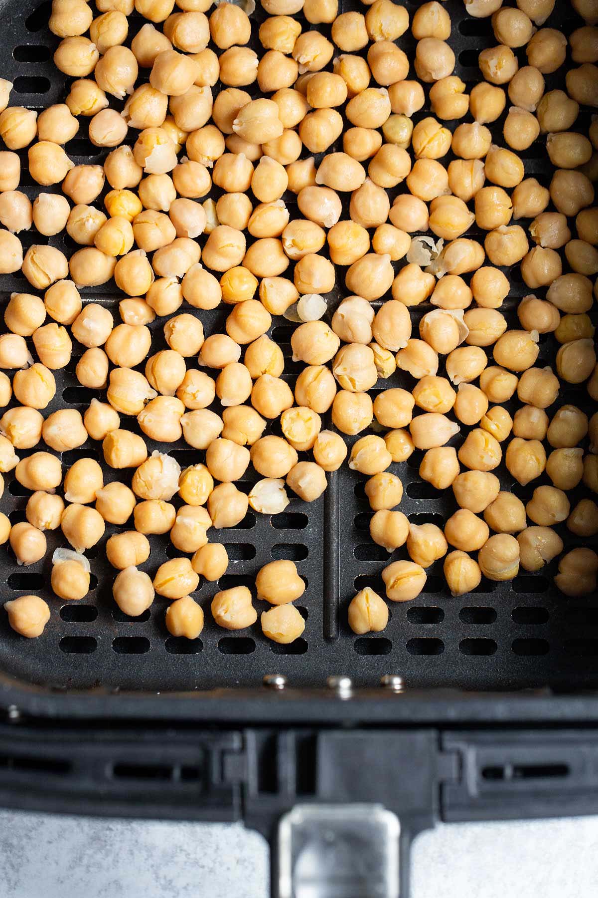 Uncooked chickpeas in air fryer basket