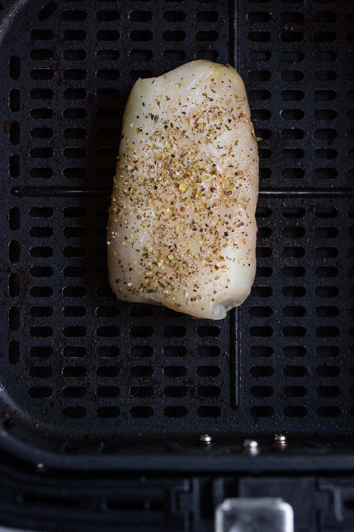 Uncooked frozen cod in air fryer basket