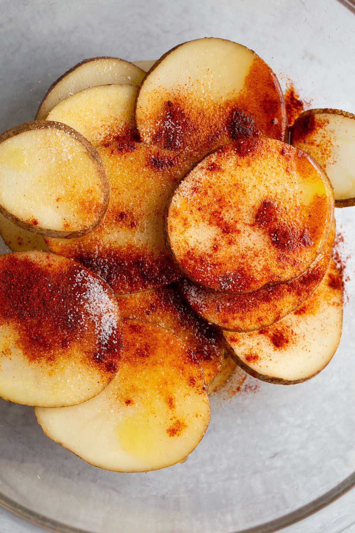 Potato slices and seasonings in a bowl