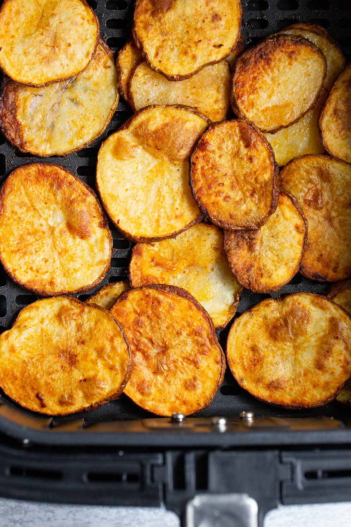 Cooked potato slices in air fryer basket