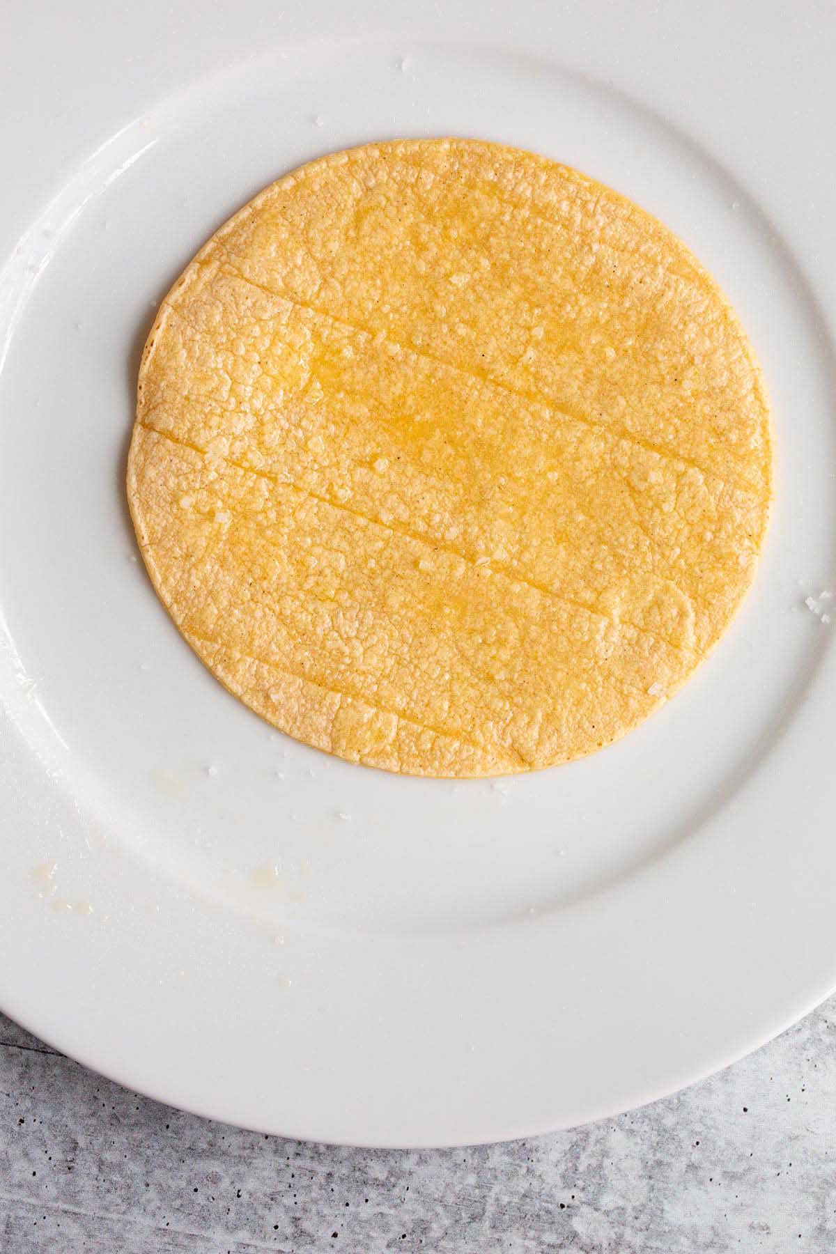 Brushing corn tortilla with oil and sprinkling with salt