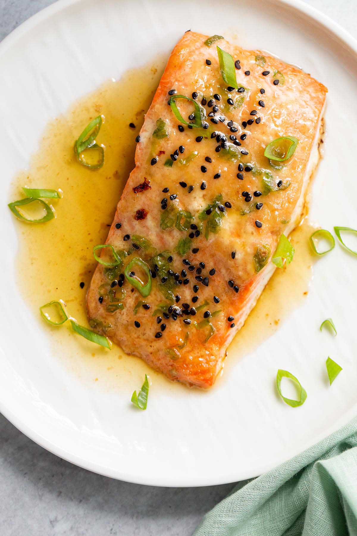 Miso butter salmon on a white plate with green onions