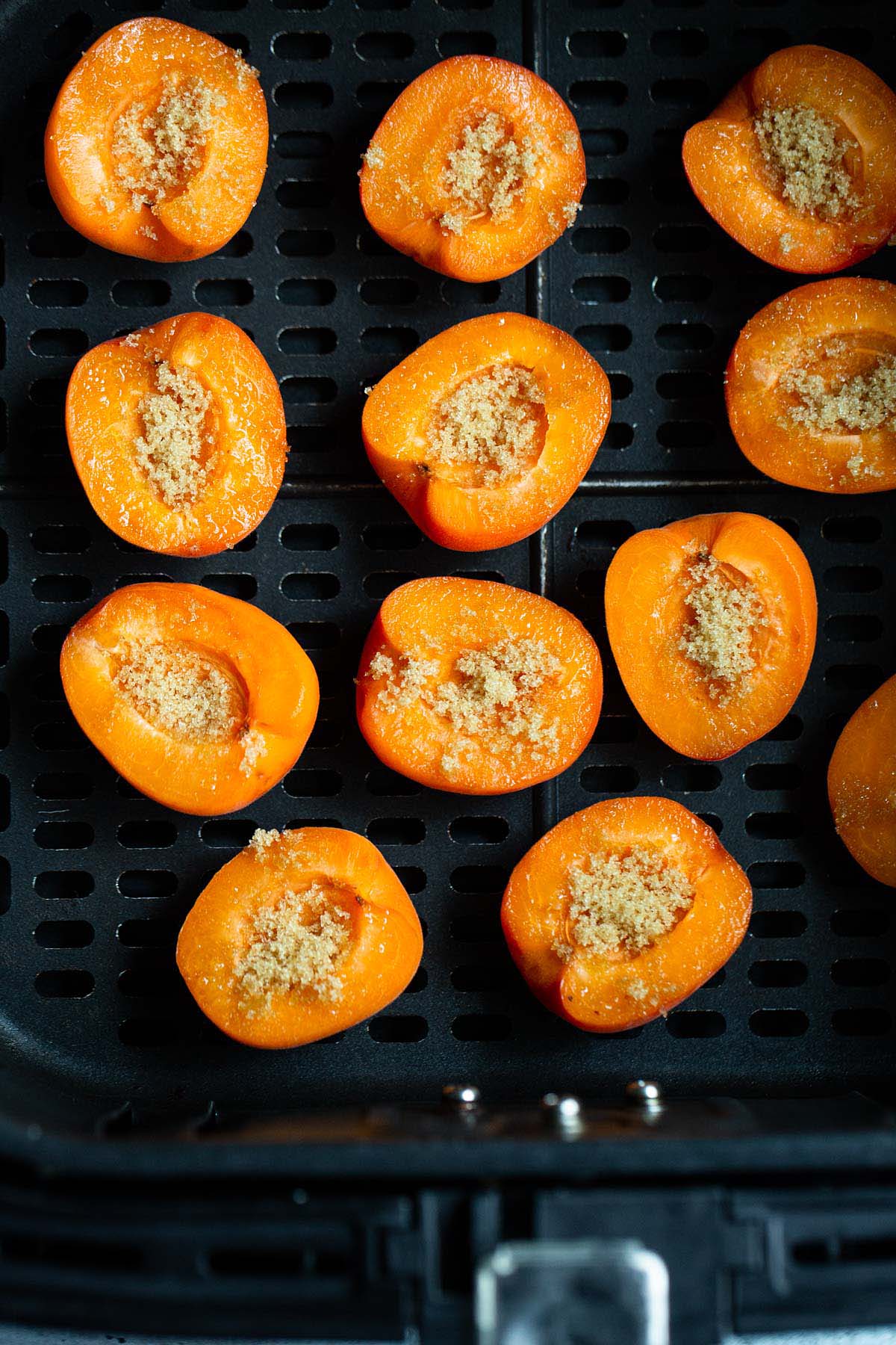 Apricots topped with brown sugar in air fryer basket.