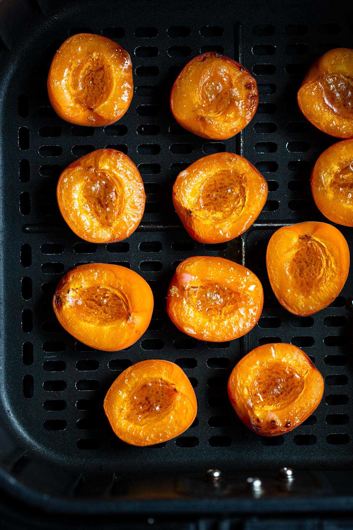 Cooked apricots in air fryer basket.