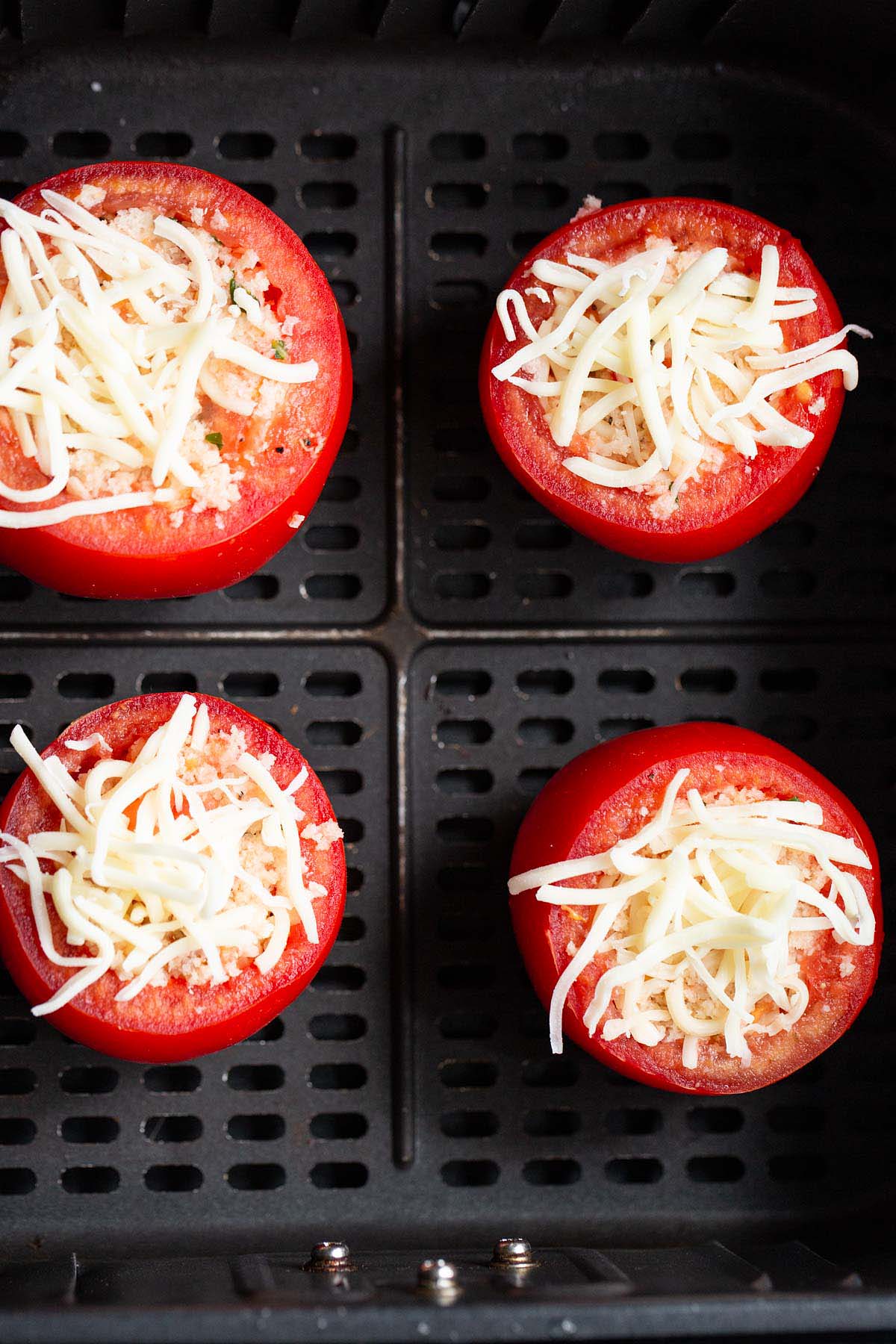 Uncooked tomatoes in air fryer basket.