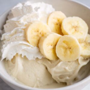 Ninja Creami banana cream pie ice cream topped with sliced bananas and whipped cream