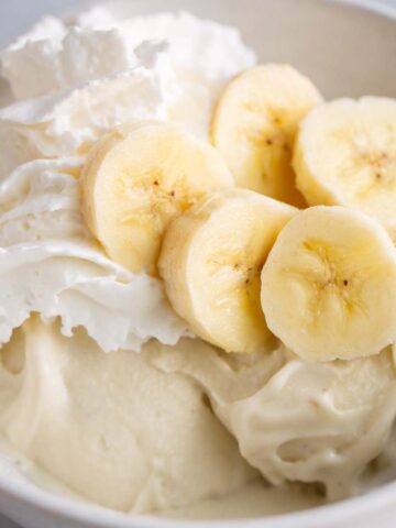 Ninja Creami banana cream pie ice cream topped with sliced bananas and whipped cream