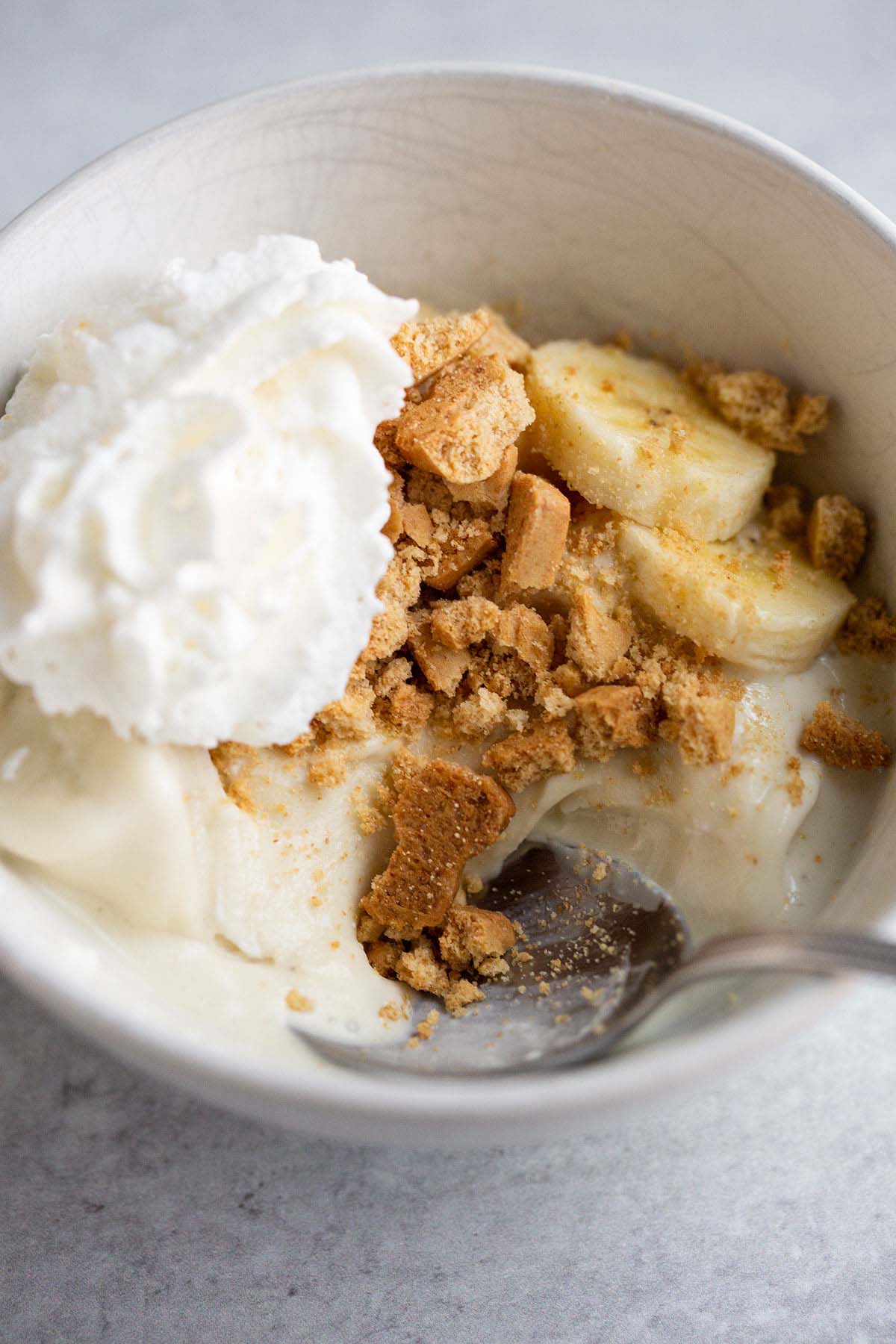 Ninja Creami banana cream pie ice cream topped with sliced bananas, graham crackers, and whipped cream