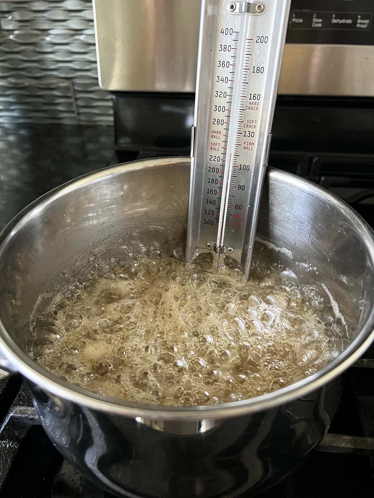 Cooking mixture for honeycomb candy on the stove with a candy thermometer