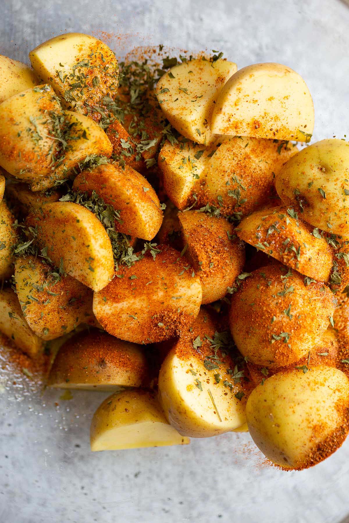 Adding seasonings to bowl of diced potatoes