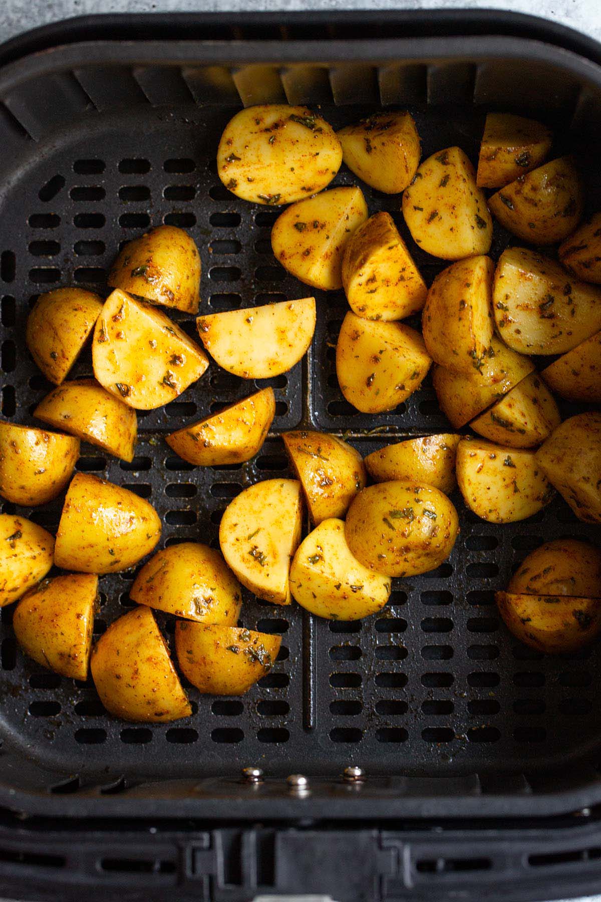 Uncooked potatoes in air fryer basket