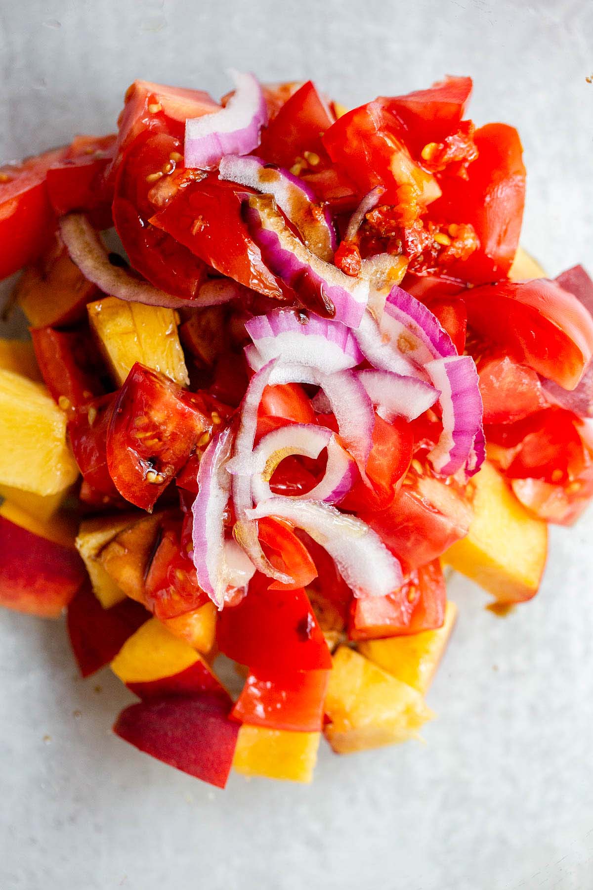 Adding ingredients to a bowl for the tomato peach salad
