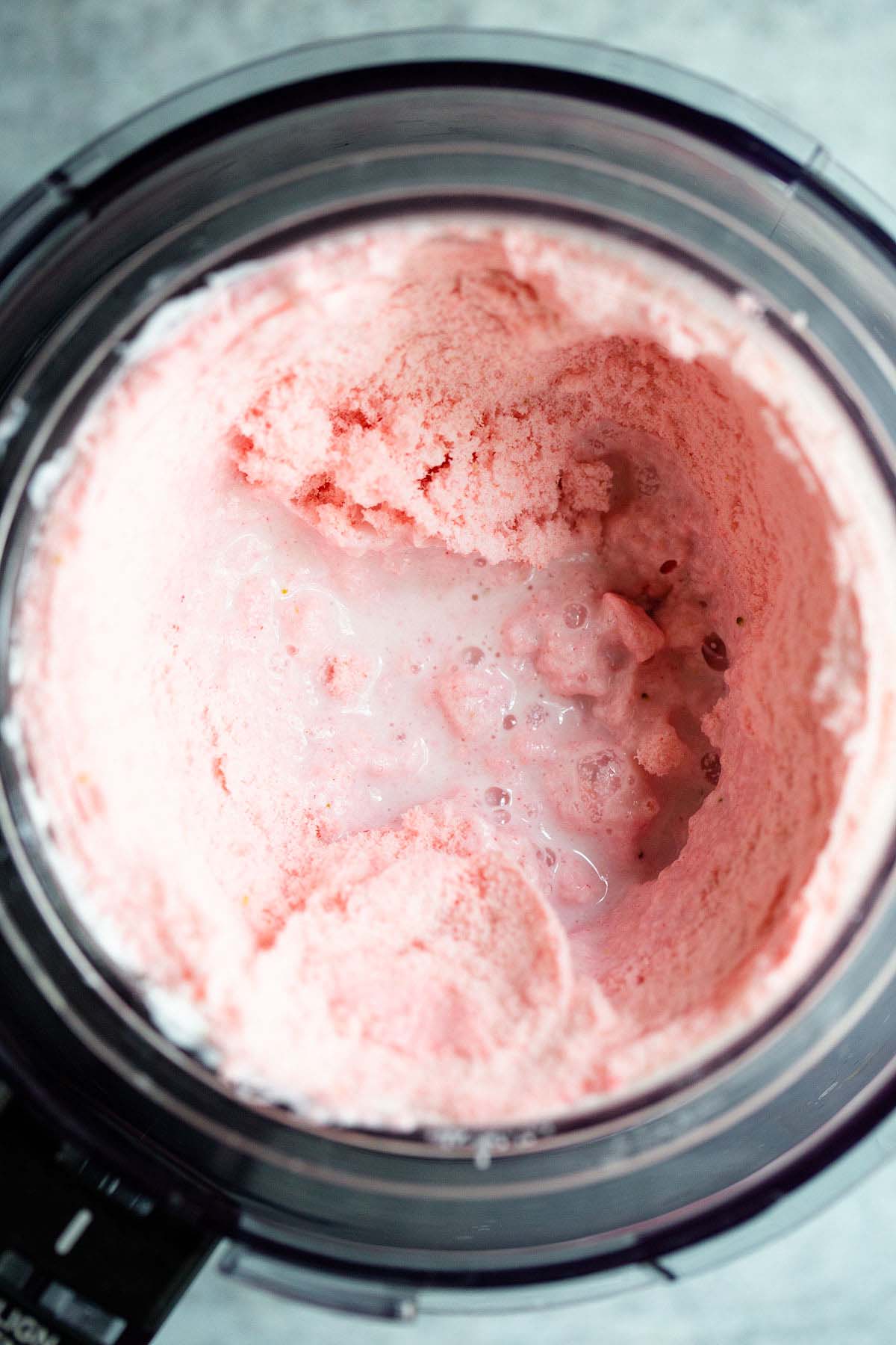 Adding a splash of milk to strawberry creami