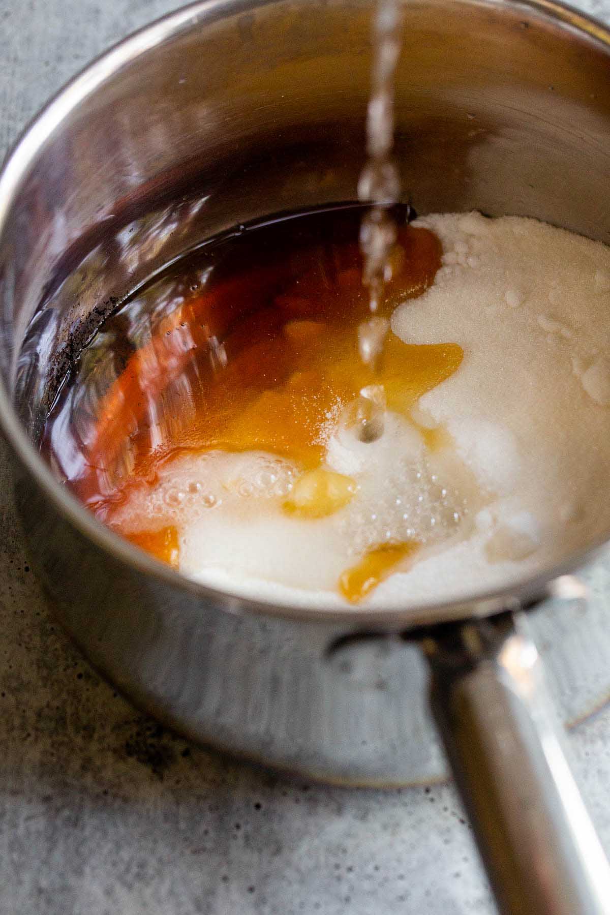 Adding water to honey and sugar in a large pot