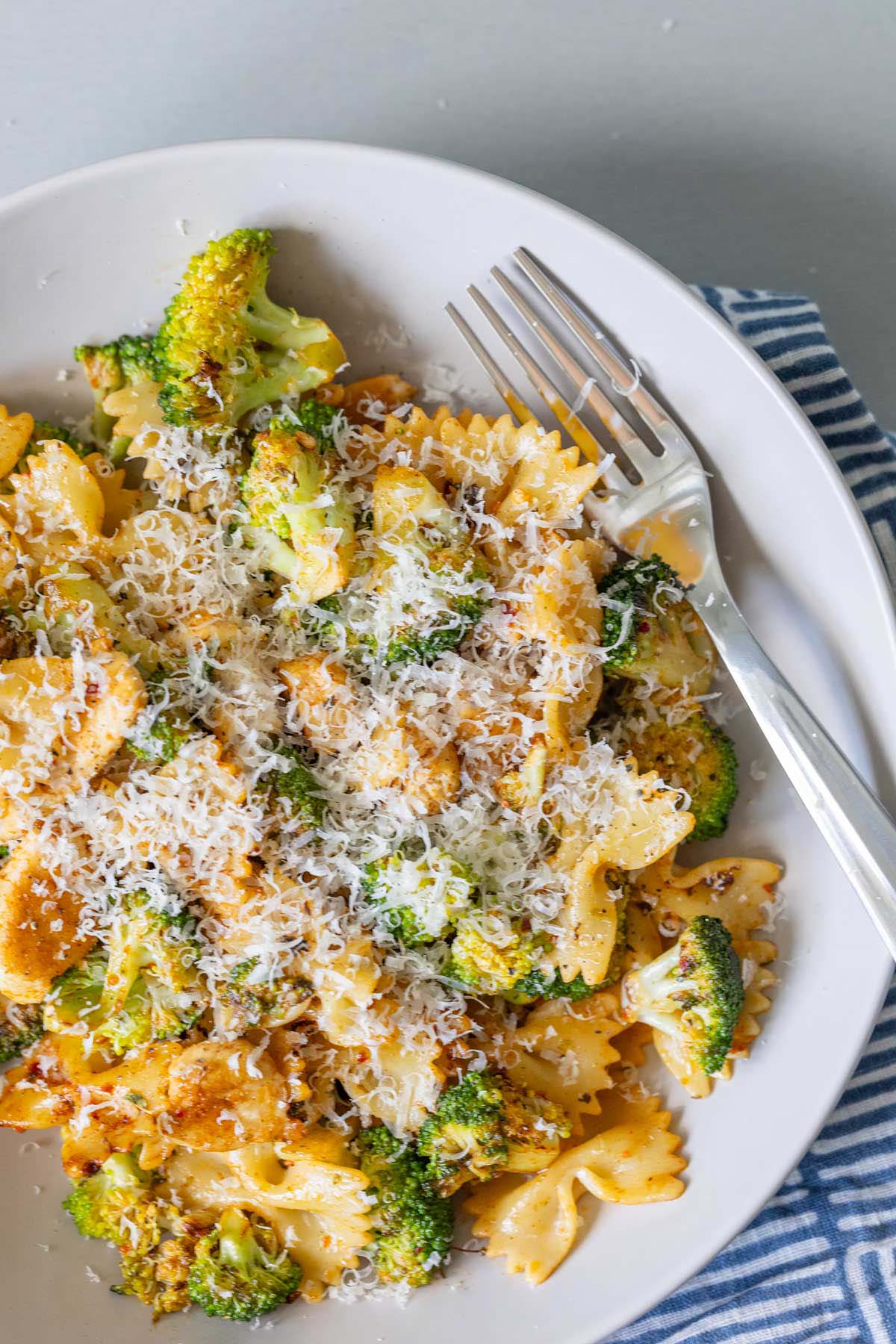 Chicken broccoli pasta in a bowl topped with parmesan cheese.