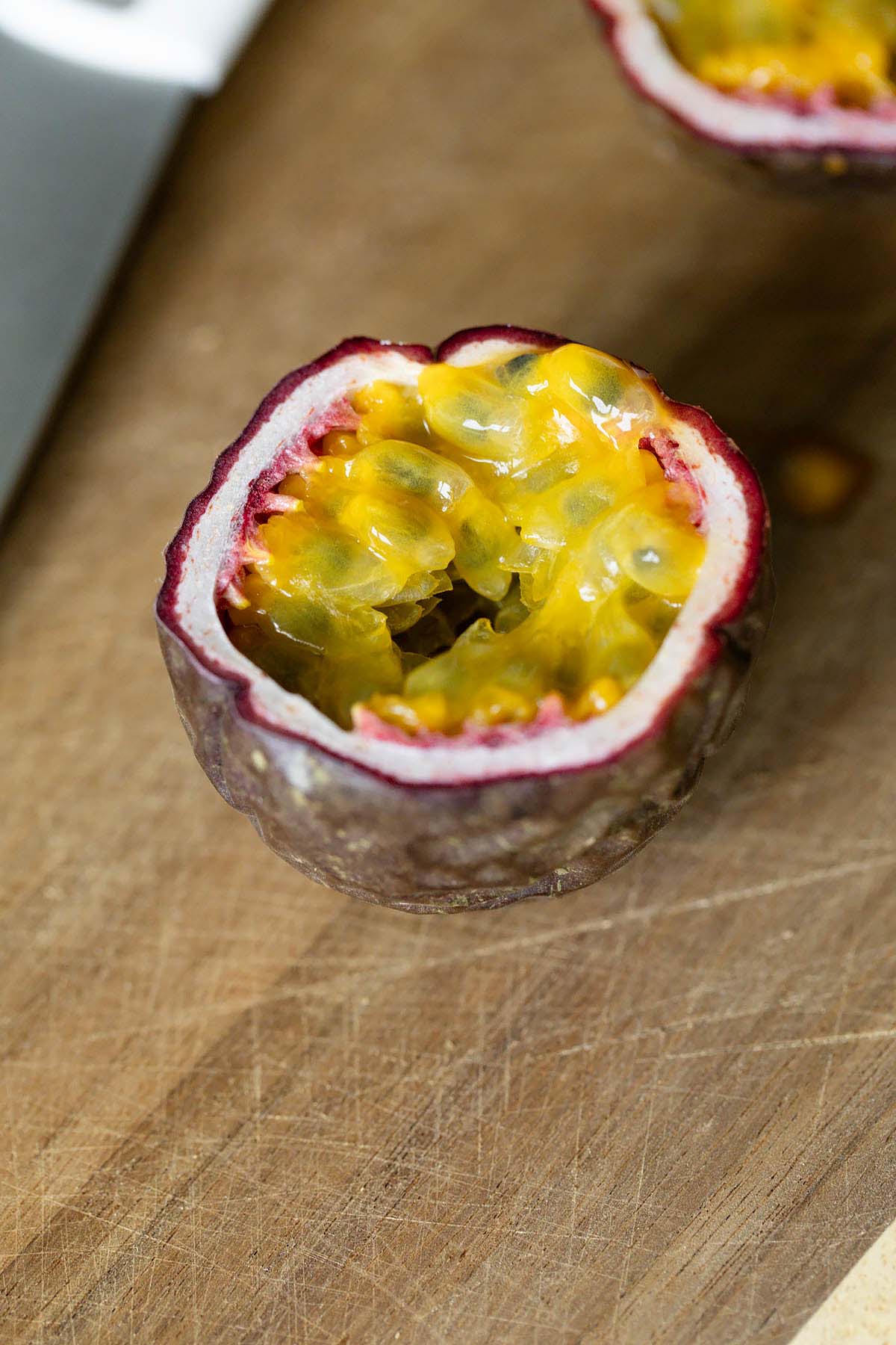 Cut passionfruit on a wooden cutting board.