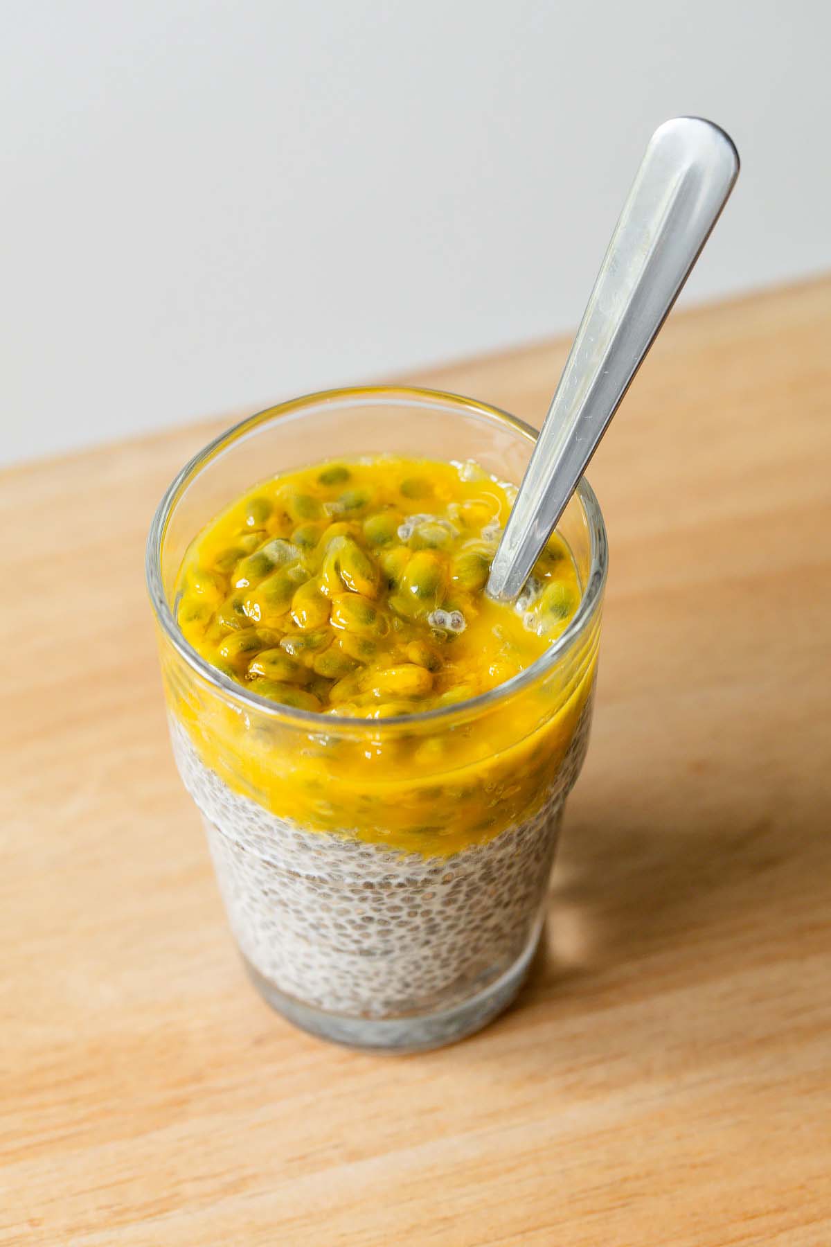 Passionfruit chia pudding in a cup with a spoon.