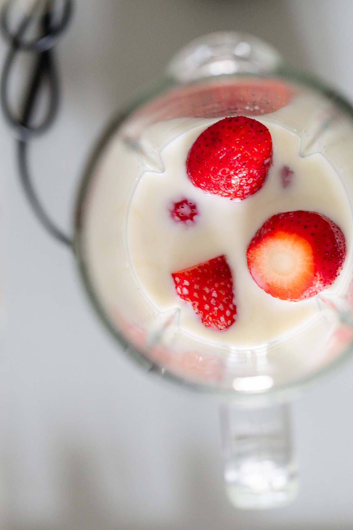 Whole strawberries, milk, and vanilla in a blender.