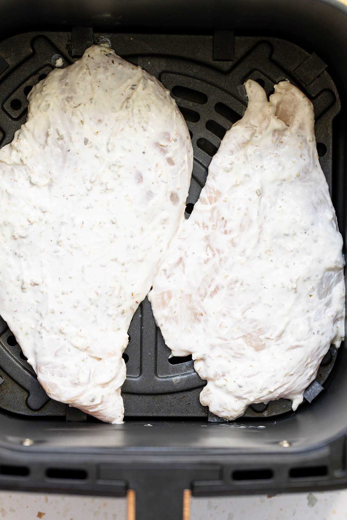 Uncooked chicken in air fryer basket