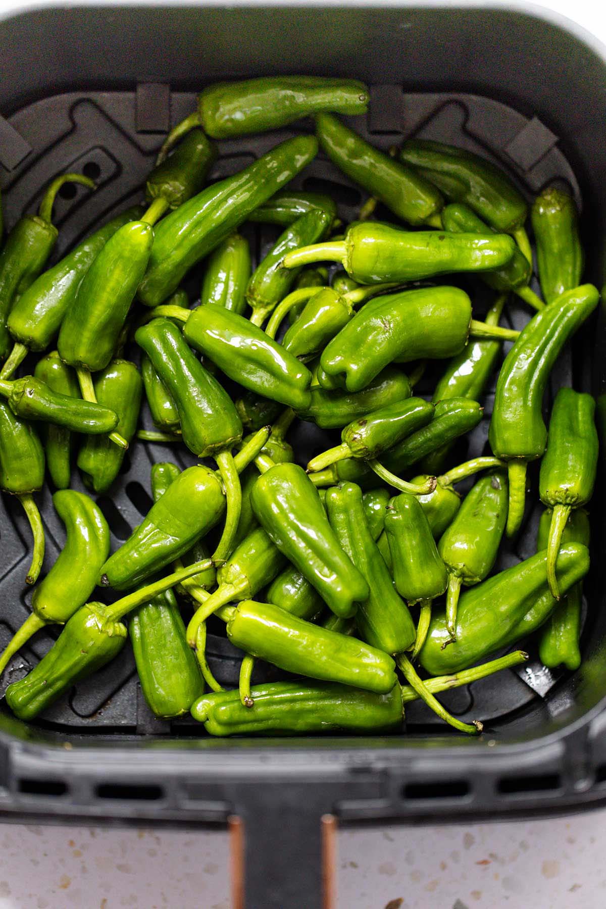 Raw padron peppers in air fryer basket
