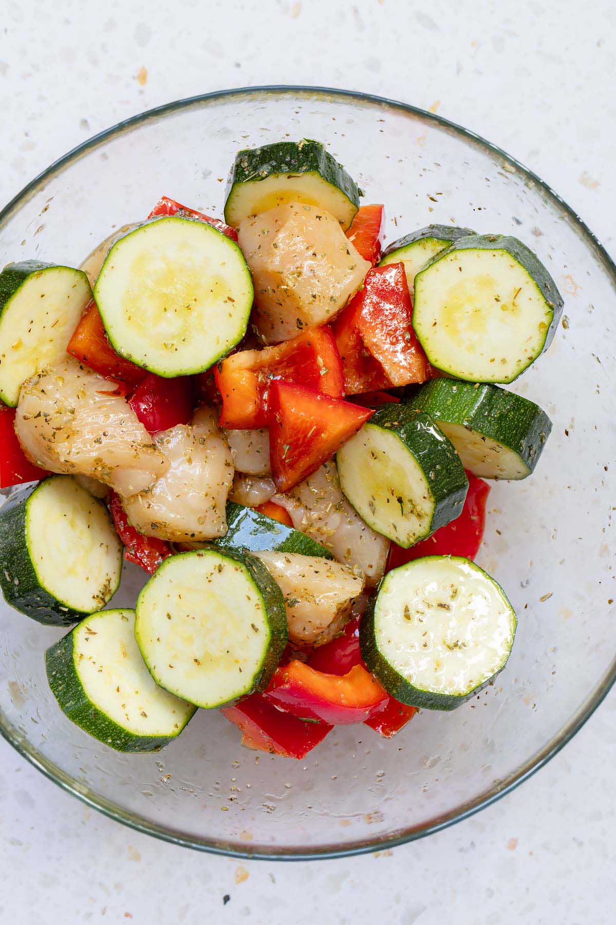 Uncooked chicken, bell pepper, and zucchini in a bowl