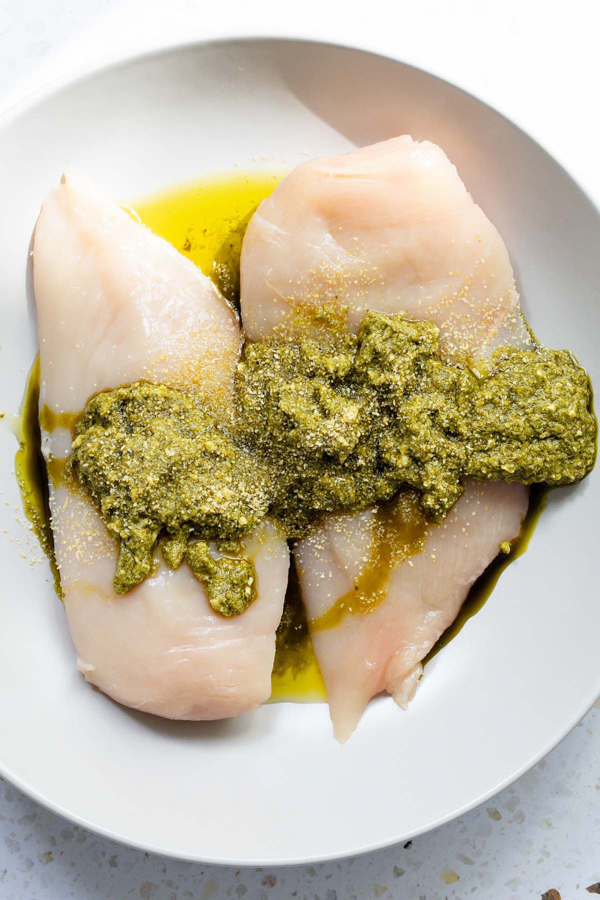 chicken in a bowl with pesto and seasonings