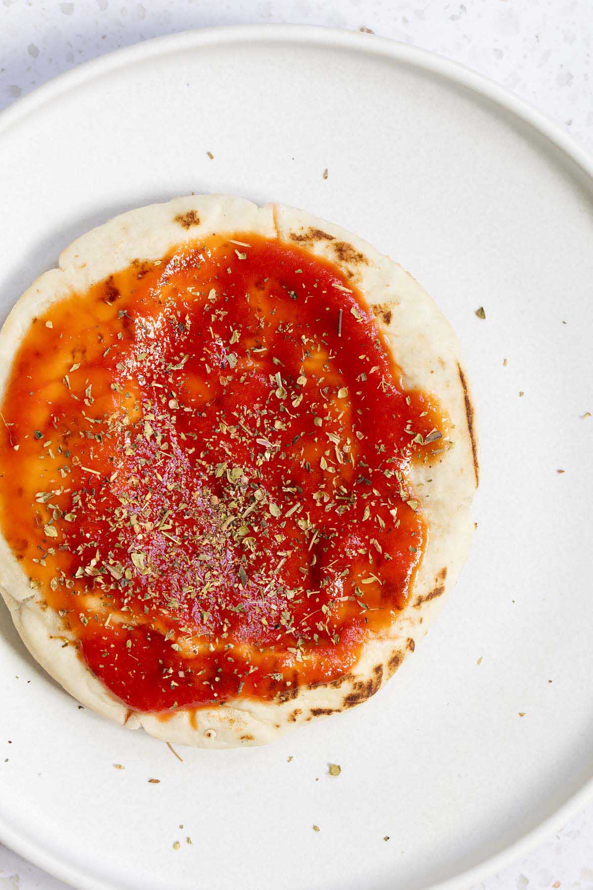 Adding sauce and seasonings to pita bread