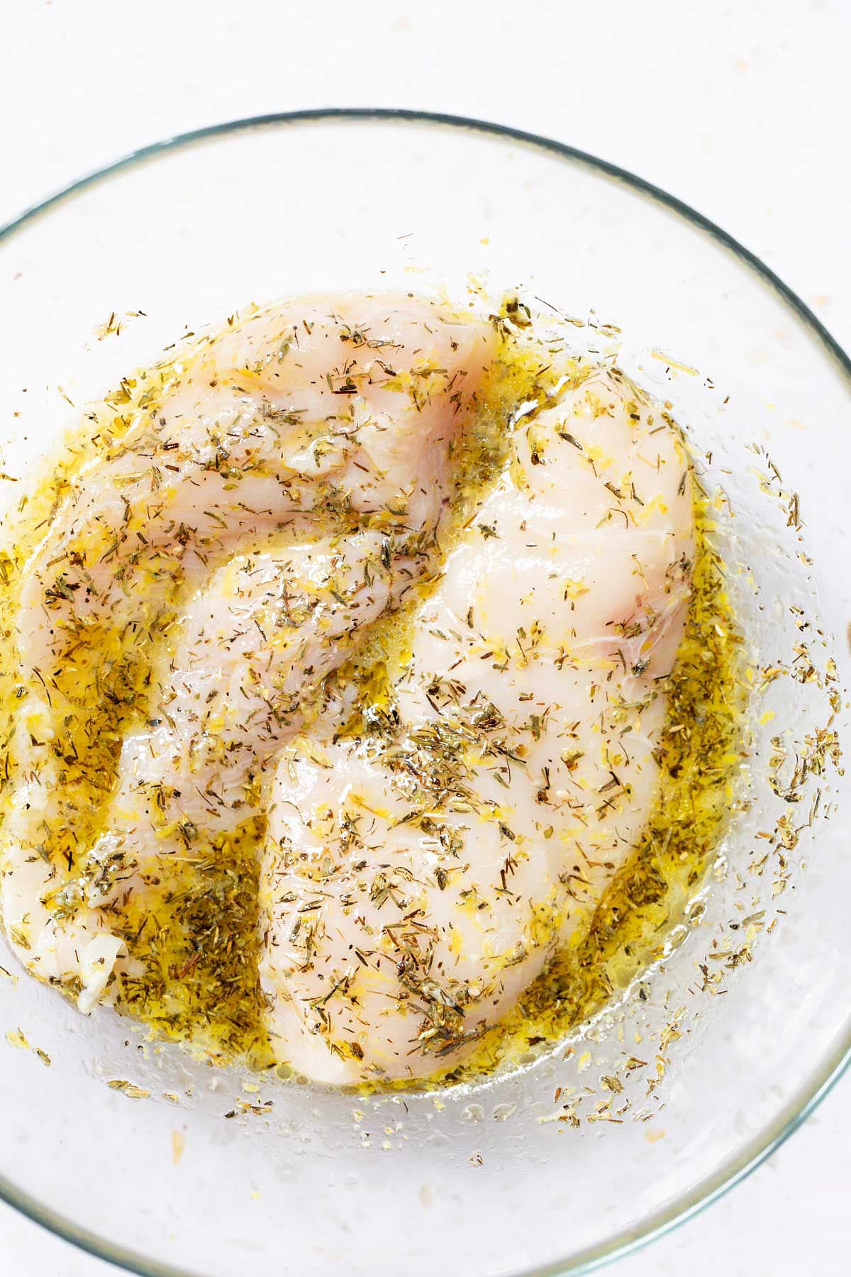 Chicken marinating in lemon, olive oil, and herbs