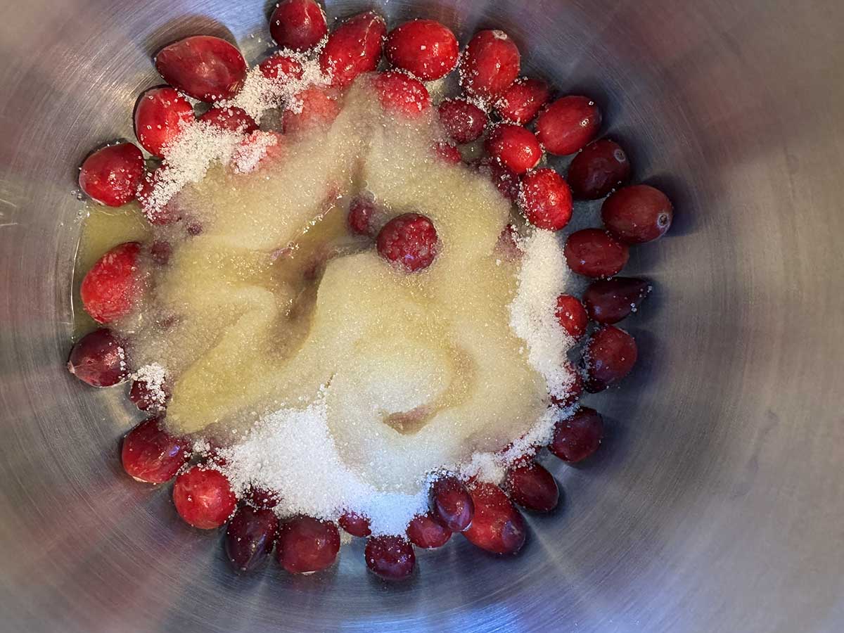 Cranberries, orange, and sugar in a pot.
