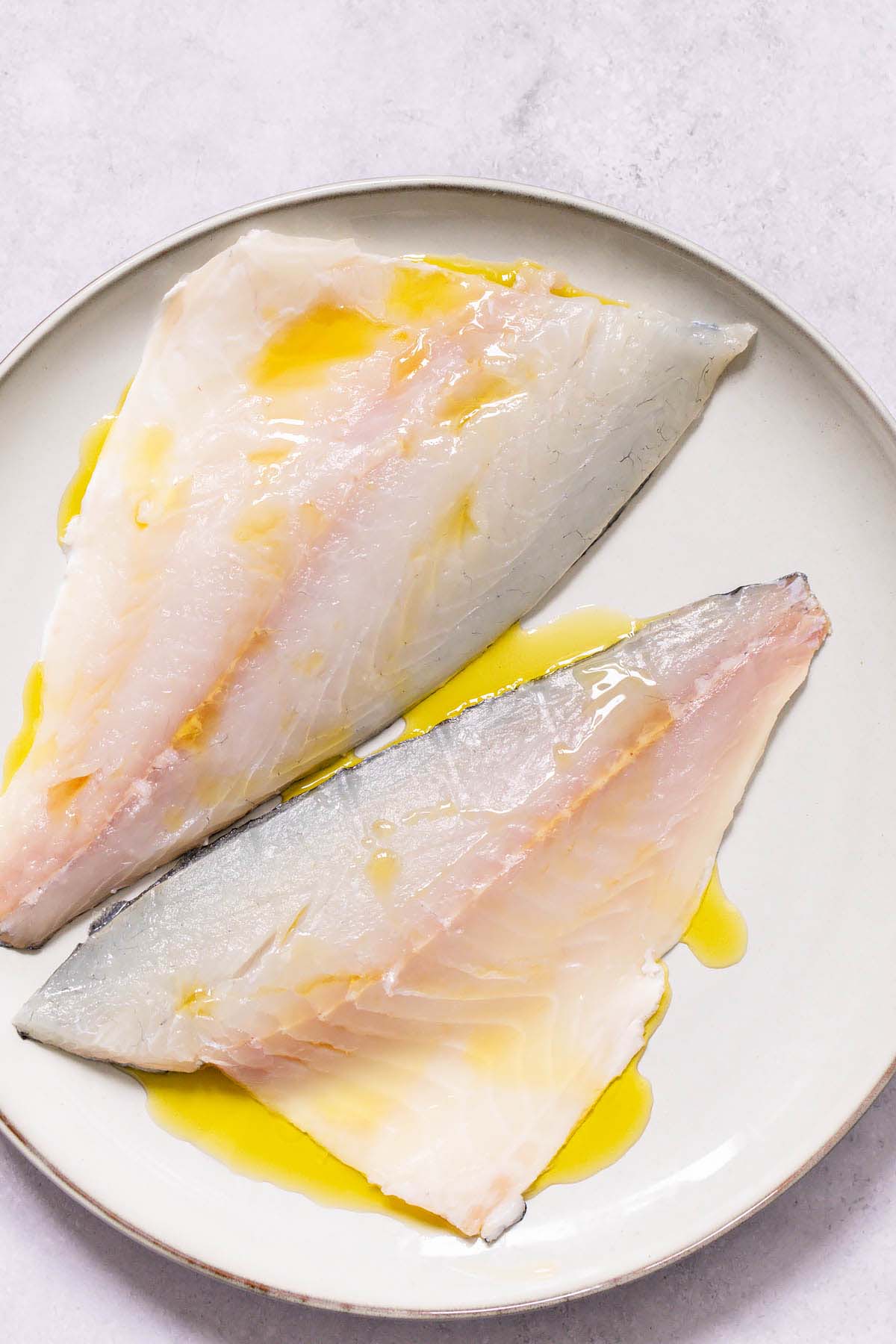 Drizzling olive oil on sea bream fillets
