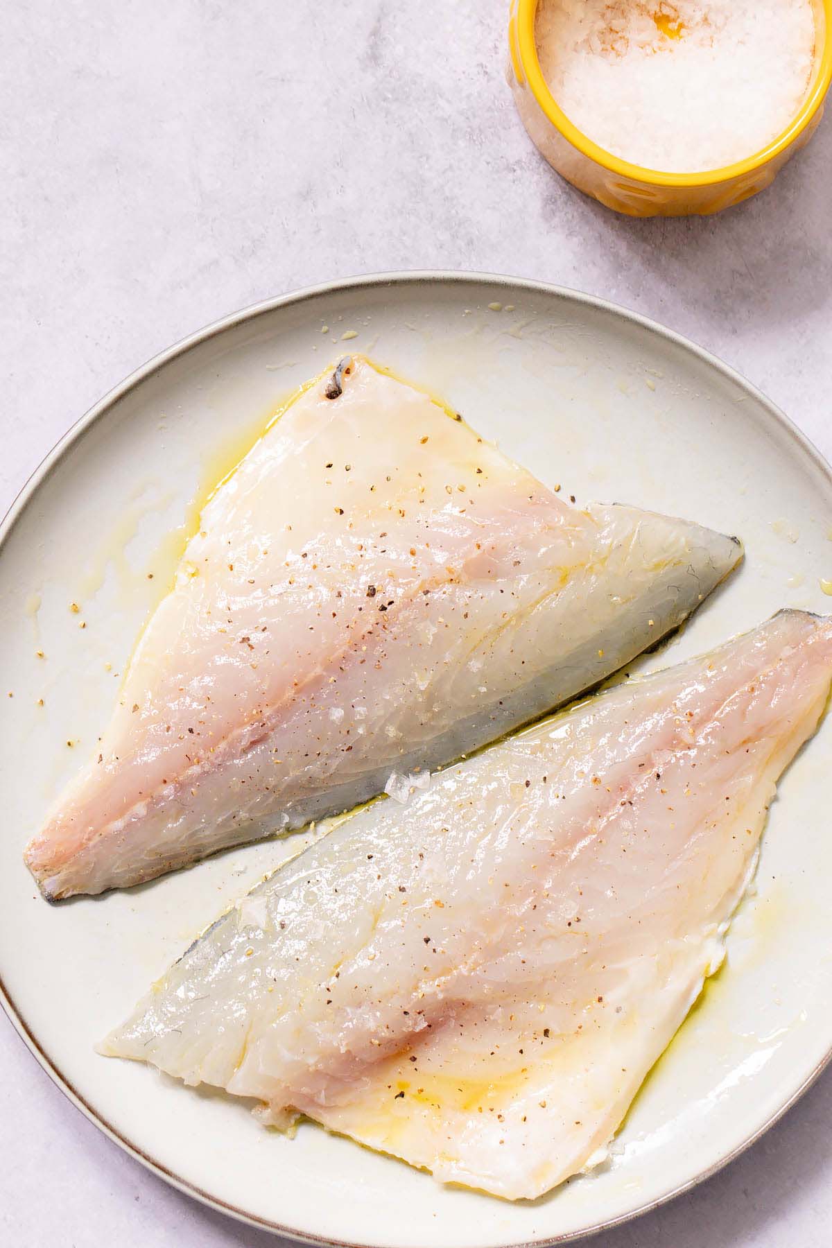 Salt and pepper on raw sea bream fillets
