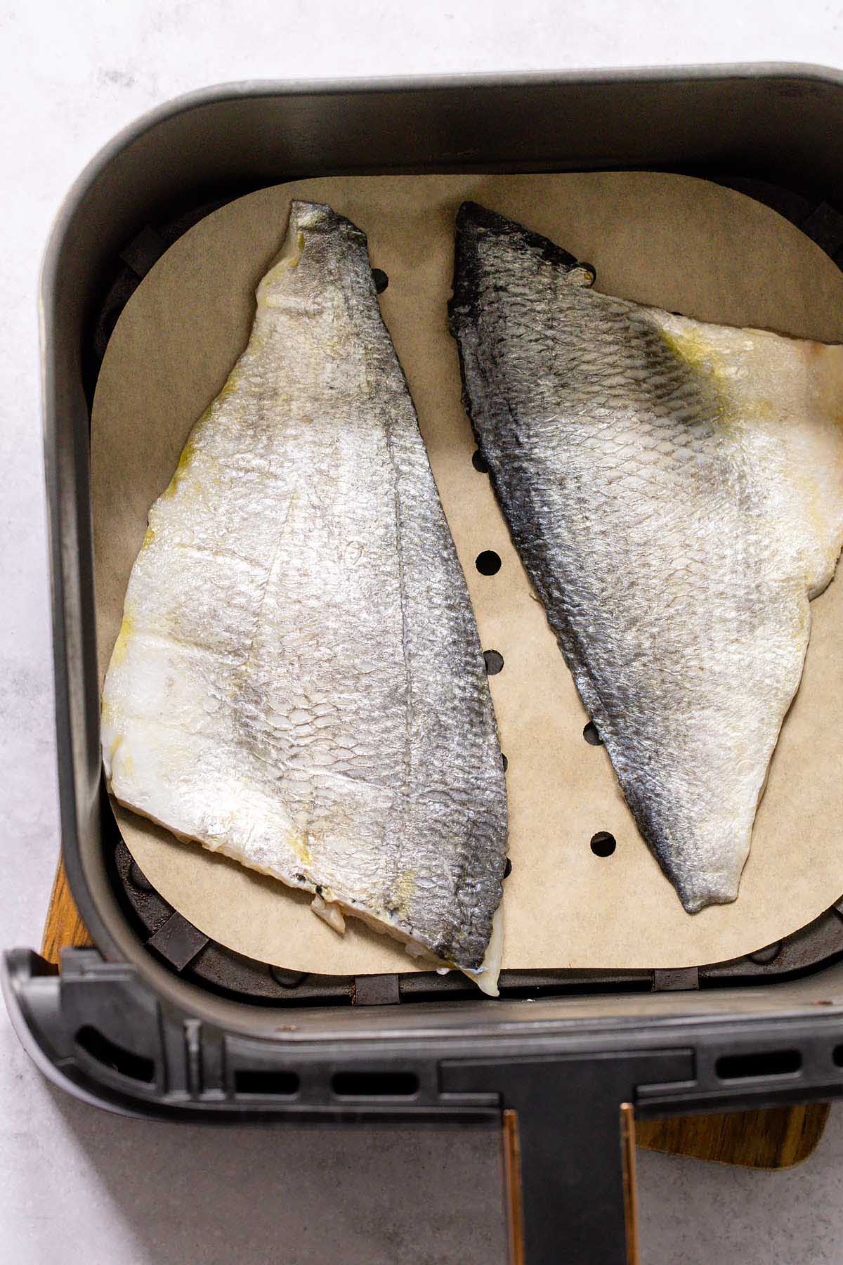 Raw sea bream fillets in air fryer basket