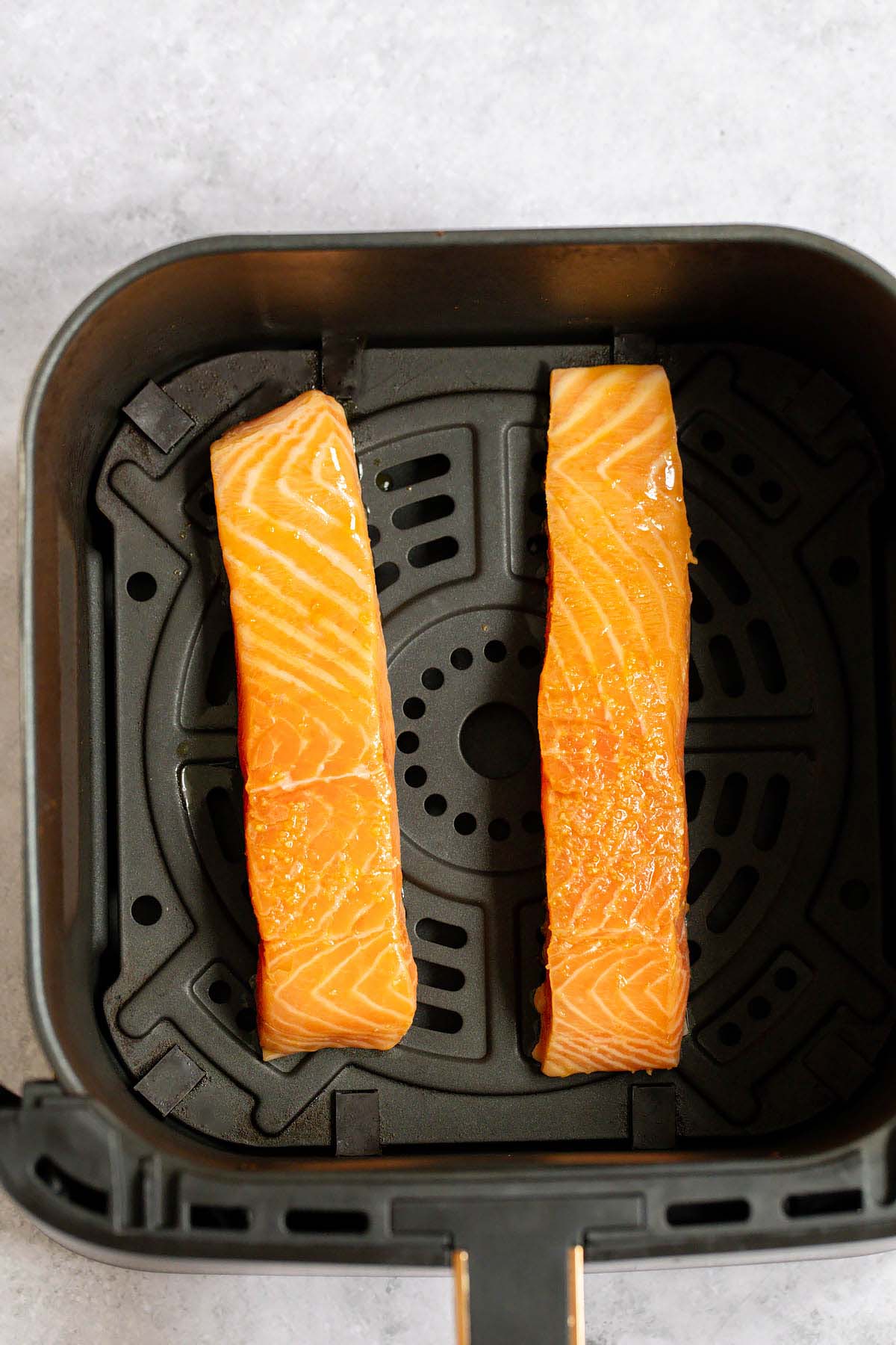 Uncooked salmon fillets in air fryer