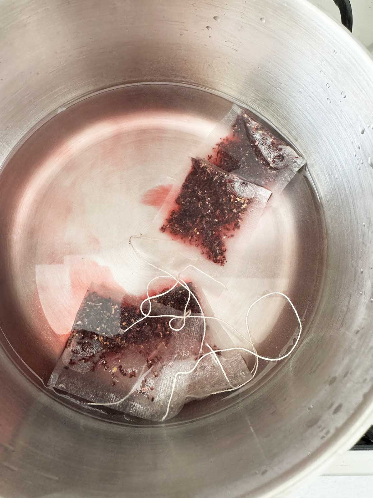 Hibiscus tea bags steeping in water in a pot