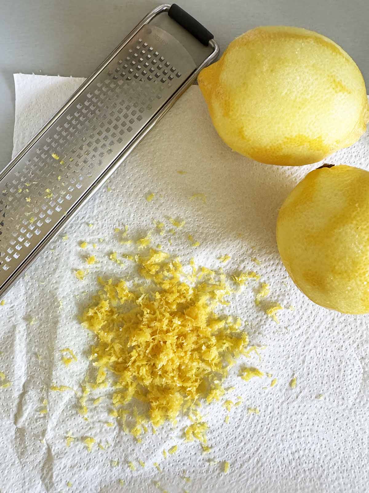 Zesting lemons - 2 zested lemons with lemon zest on a paper towel