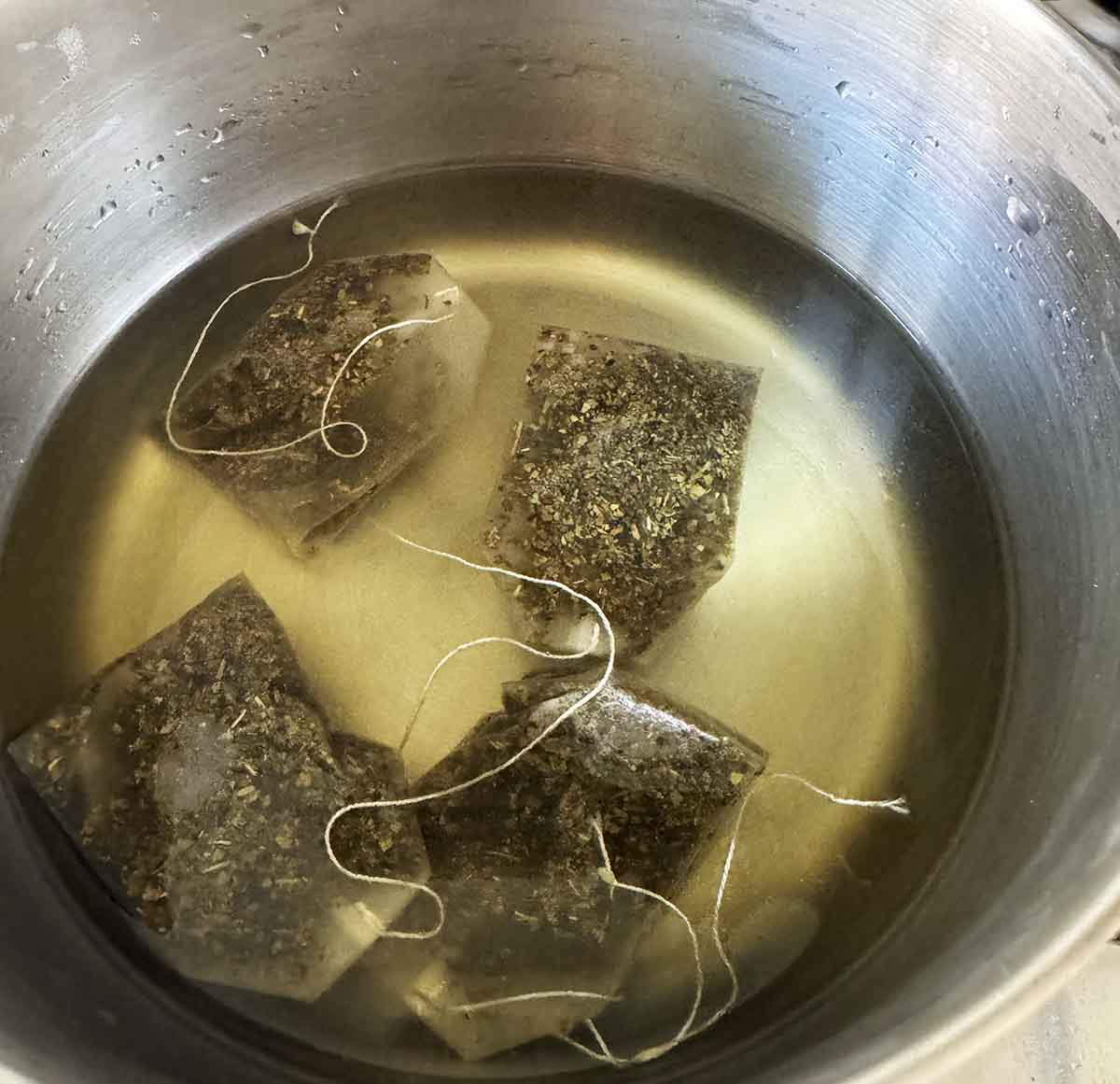 Adding four tea bags to hot water