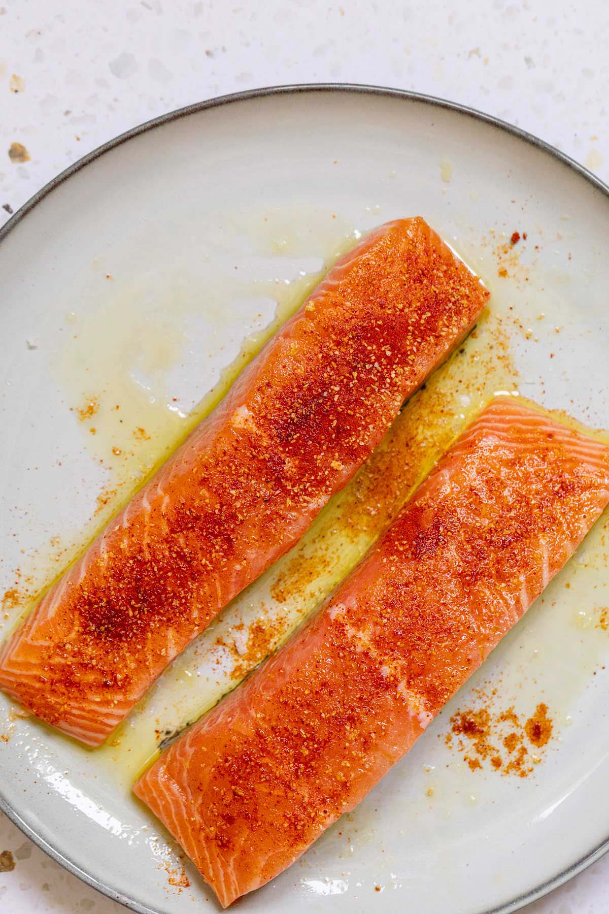 Raw salmon seasoned with olive oil and seasonings on a plate